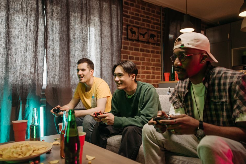 Three diverse friends playing video games together at home, enjoying leisure time.