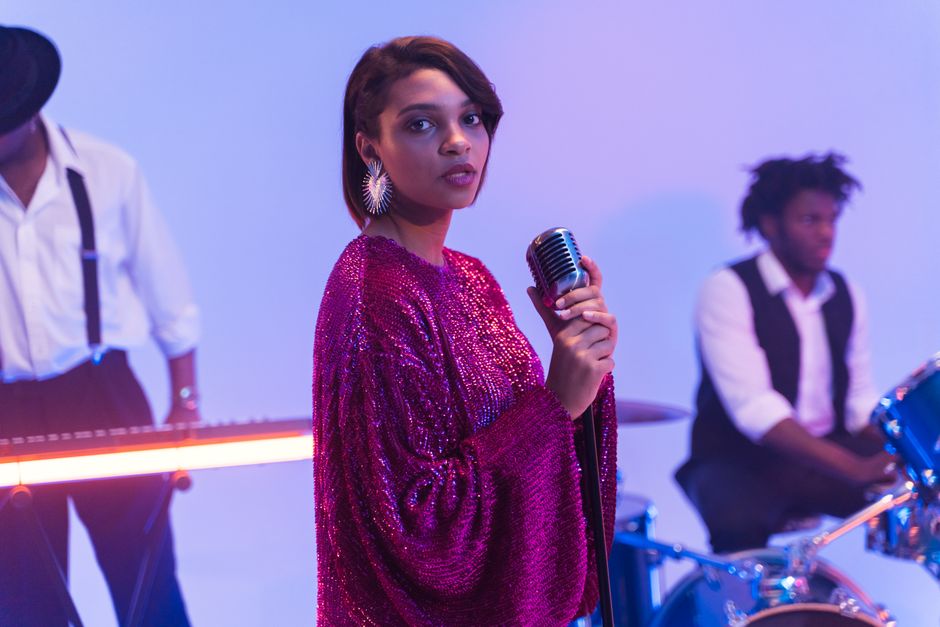A vibrant performance featuring a stylish singer in a band setting with a retro microphone.