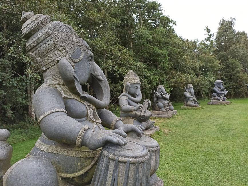 Stone statues of Ganesha playing musical instruments in an Irish garden.