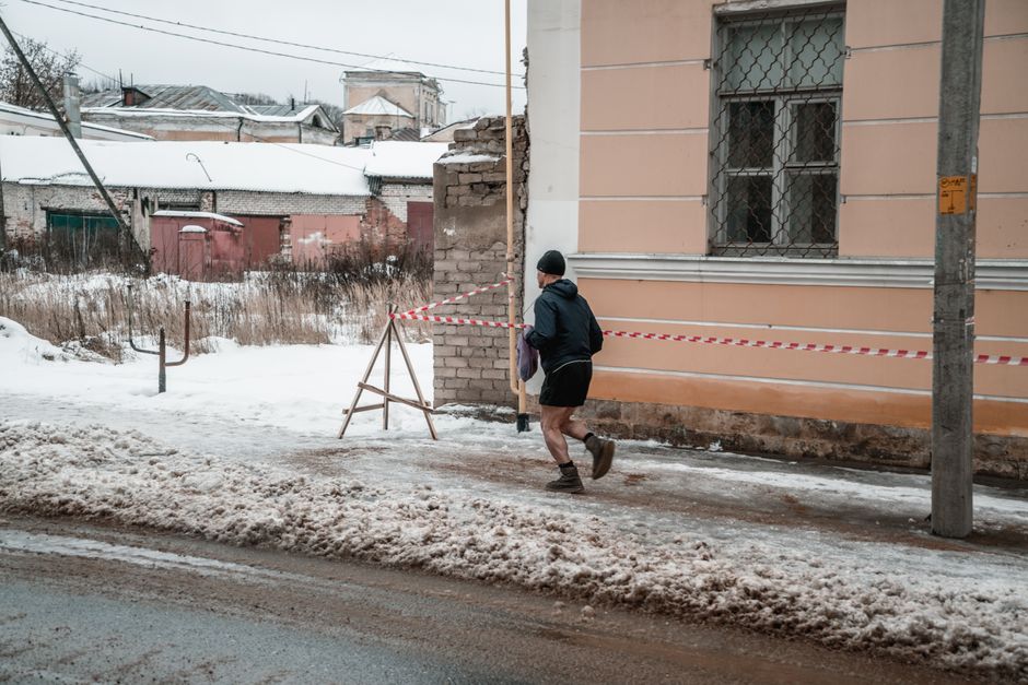 Man jogging on a snowy street in urban setting during winter, defying cold weather.