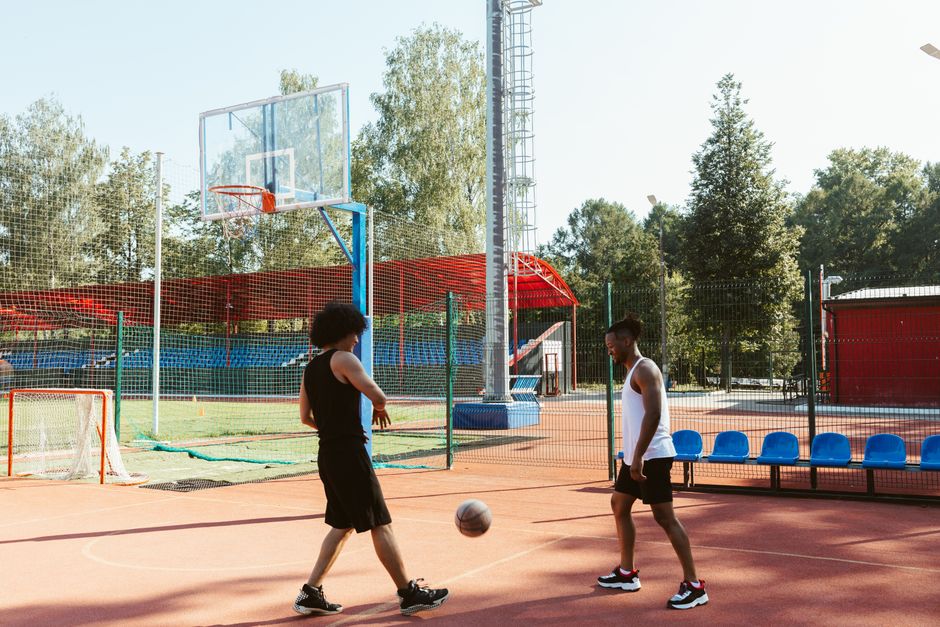 Two men playing basketball on an outdoor court during the day.