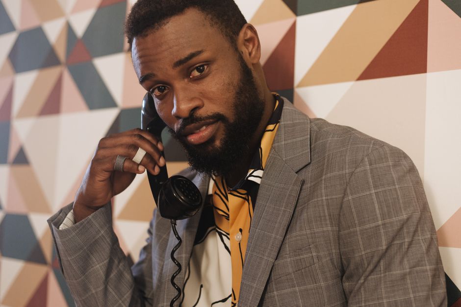 Stylish man in a suit holding a vintage telephone against geometric background.