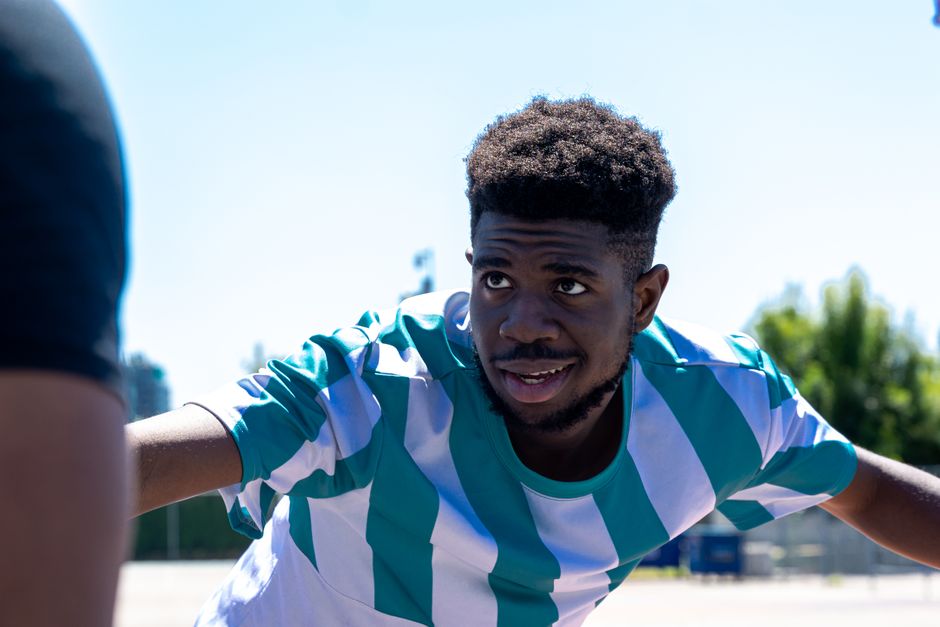A young man in a striped shirt enjoying sports outdoors on a sunny day.